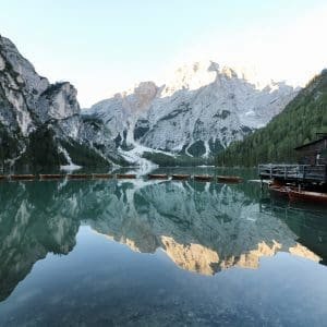 Morning glow at Lake Prags, with the rowboats lined up on the shore and the sun painting the sky in hues of orange and pink, South Tyrol, Italy