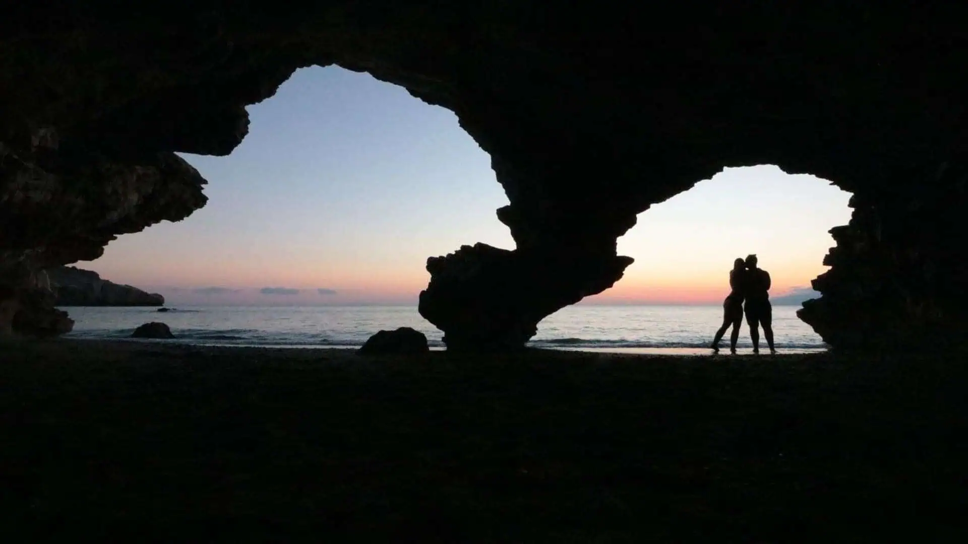 Couple kissing in twin Cave Agios Pavlos at sunset