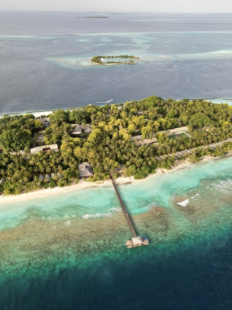 Drone shot of the lush green Royal Island Resort withe the beautiful house reef in the foreground