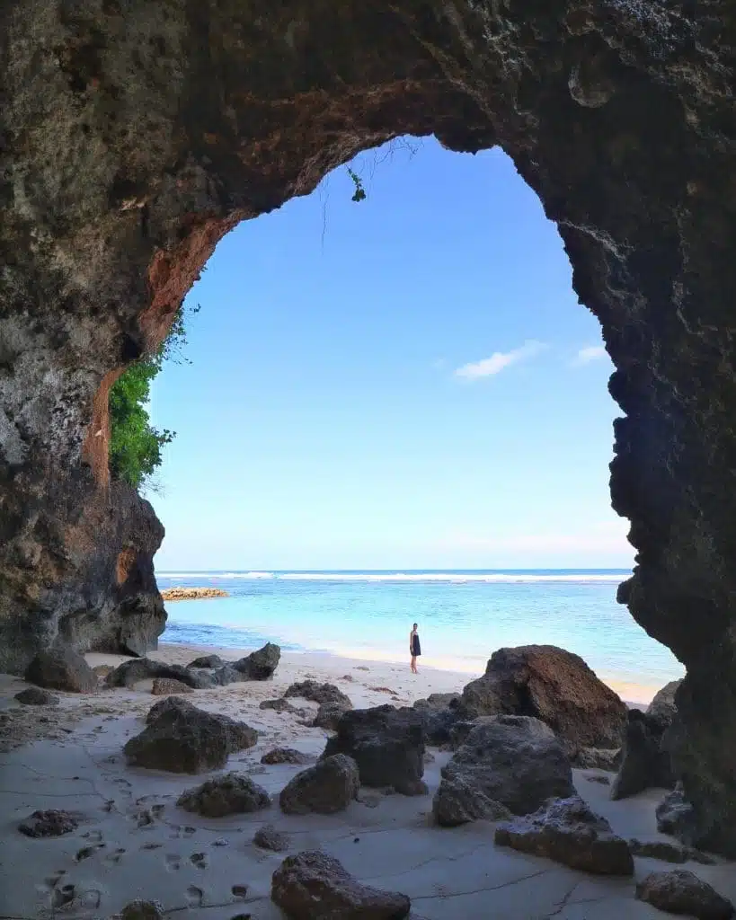 a cave with a person standing on the beach