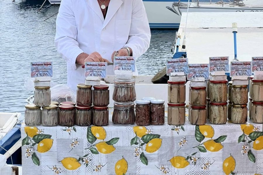 a man standing at a table with jars of fish